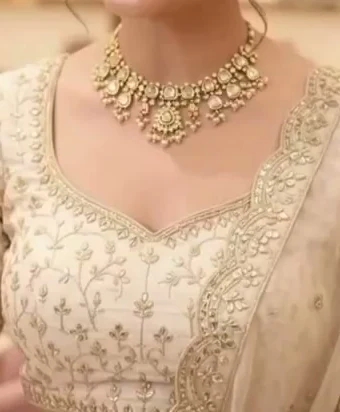 Bride wearing a statement choker necklace with an embroidered ivory lehenga